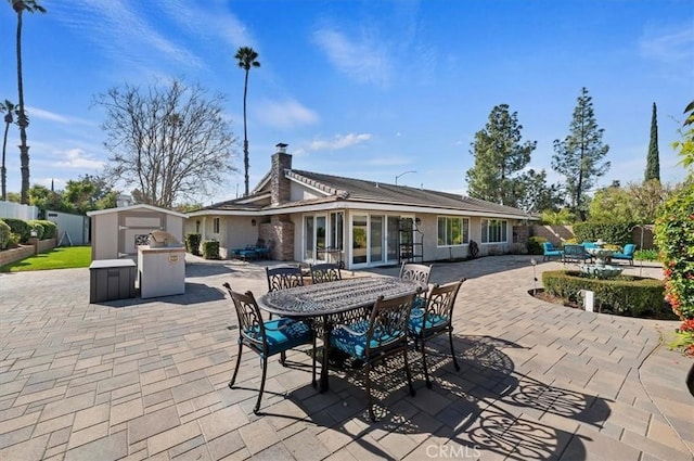 view of patio featuring outdoor dining space, an outdoor structure, and a storage unit