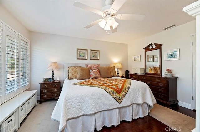 bedroom featuring a ceiling fan, visible vents, baseboards, and wood finished floors