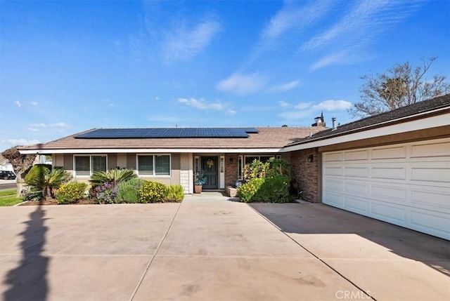 view of front of property with a garage, solar panels, and concrete driveway