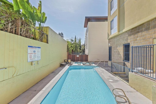 community pool with fence and a patio