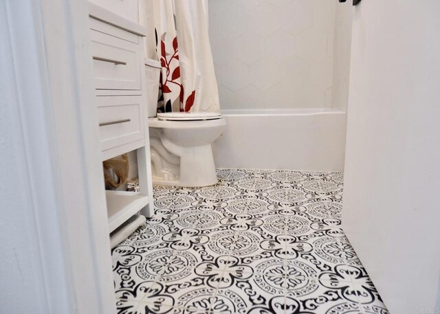bathroom featuring toilet and shower / bath combination with curtain