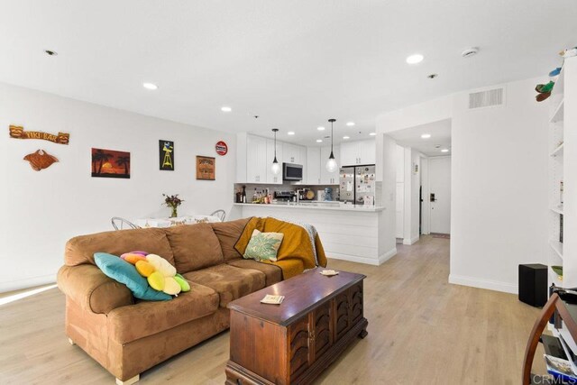 living room with light wood-type flooring, recessed lighting, and baseboards