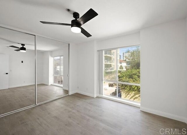 unfurnished bedroom featuring multiple windows, wood finished floors, and baseboards