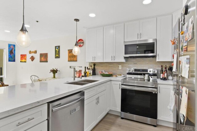 kitchen with appliances with stainless steel finishes, white cabinetry, recessed lighting, tasteful backsplash, and pendant lighting