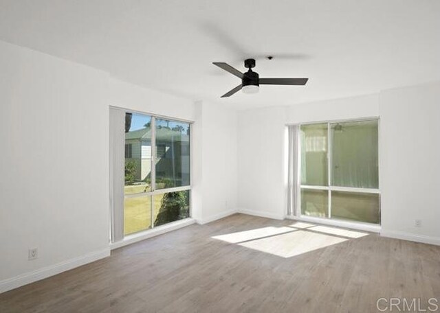 unfurnished room with wood finished floors, baseboards, and ceiling fan