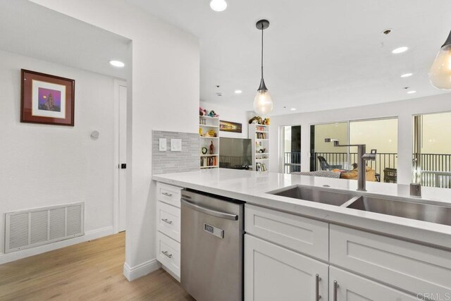 kitchen with dishwasher, a sink, white cabinets, baseboards, and light wood-style floors