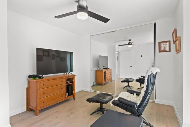 exercise room with a ceiling fan, light wood finished floors, and baseboards