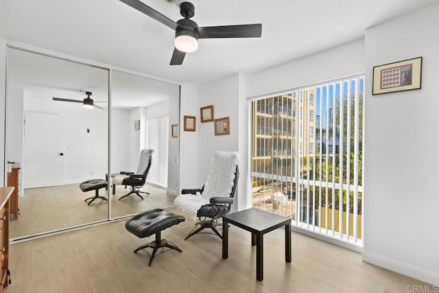 living area featuring ceiling fan, light wood-style floors, and baseboards