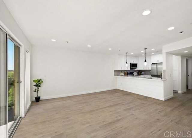 unfurnished living room with recessed lighting, baseboards, and light wood-style floors