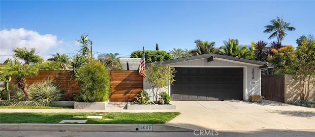 view of front of house with driveway, an attached garage, and fence