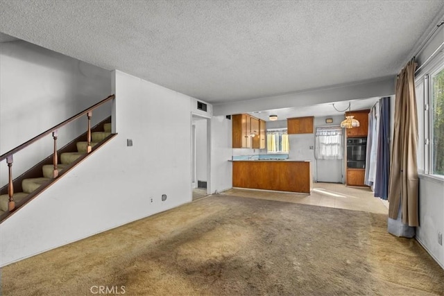 unfurnished living room with light carpet, stairway, a textured ceiling, and visible vents