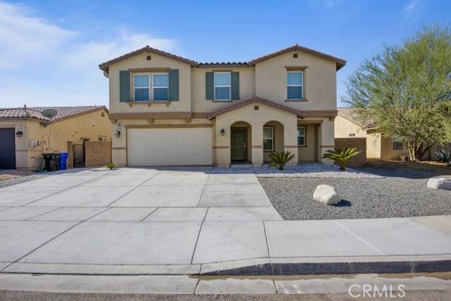 mediterranean / spanish-style home with concrete driveway, a tile roof, an attached garage, and stucco siding