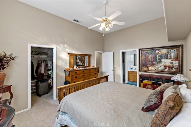 bedroom with light carpet, visible vents, ceiling fan, a walk in closet, and a closet