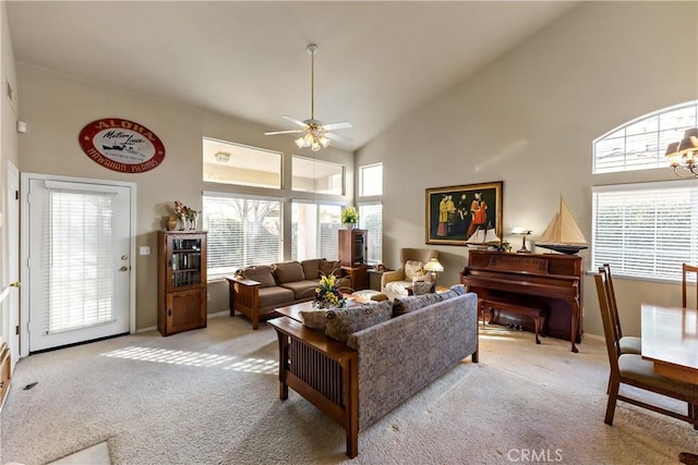 living room featuring high vaulted ceiling, light colored carpet, and ceiling fan with notable chandelier