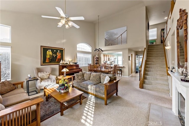 living room featuring stairs, ceiling fan, a towering ceiling, and light colored carpet