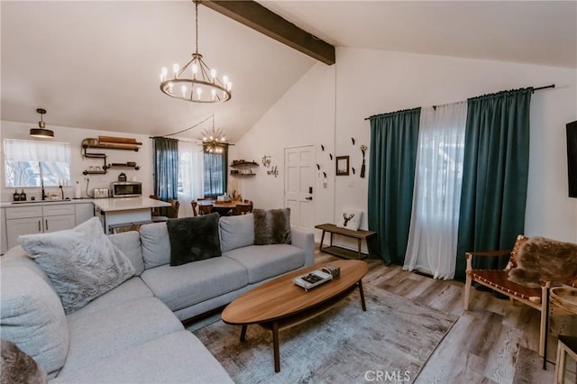 living area with lofted ceiling with beams, light wood-style floors, and an inviting chandelier