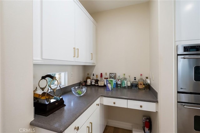 kitchen featuring dark countertops, stainless steel double oven, and white cabinetry