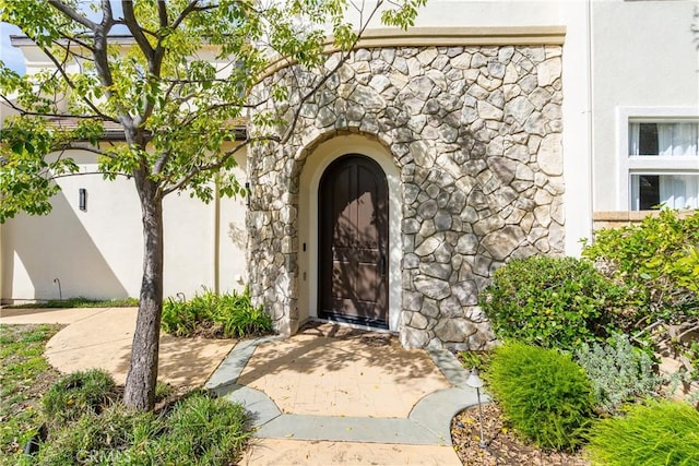 entrance to property featuring stucco siding and stone siding