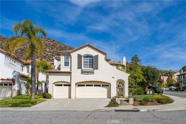 mediterranean / spanish house with a tile roof, stucco siding, an attached garage, a mountain view, and driveway