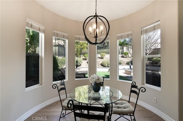dining area with baseboards, a wealth of natural light, wood finished floors, and an inviting chandelier