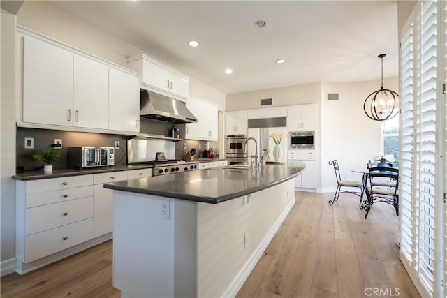 kitchen with visible vents, dark countertops, under cabinet range hood, light wood finished floors, and recessed lighting