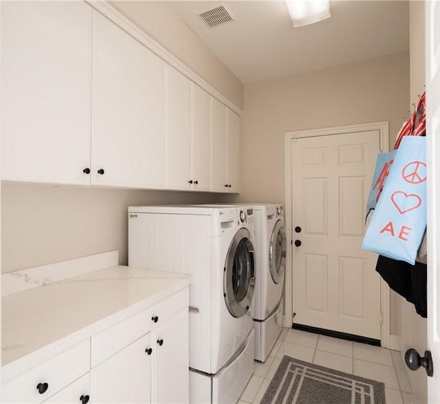 clothes washing area with cabinet space, visible vents, washer and dryer, and light tile patterned floors