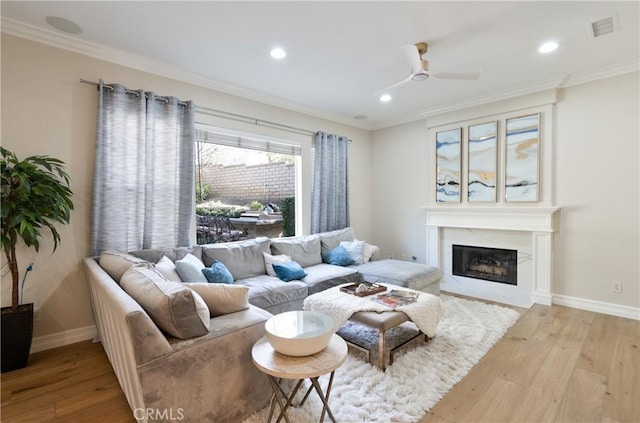 living area featuring wood-type flooring, a glass covered fireplace, visible vents, and recessed lighting