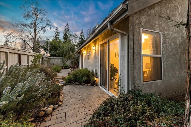 property exterior at dusk with a patio area, a fenced backyard, and stucco siding