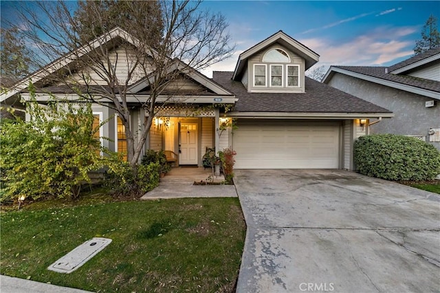 view of front of house with driveway, a shingled roof, a garage, and a front yard