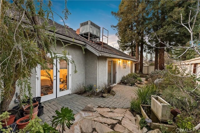 rear view of house featuring a patio, fence, french doors, central AC, and stucco siding