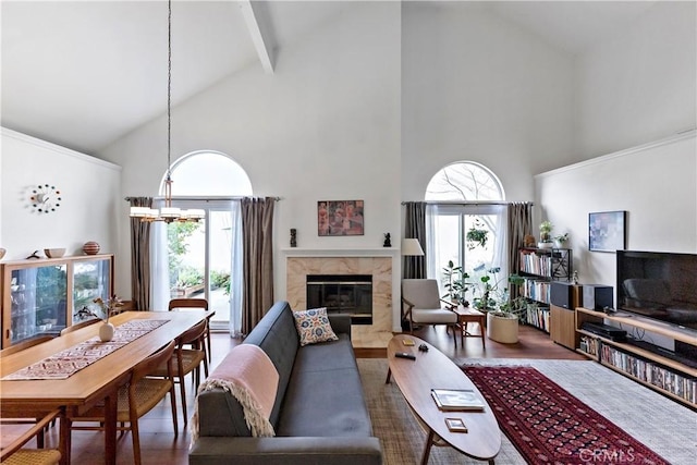 living area featuring a chandelier, a high end fireplace, beam ceiling, and a healthy amount of sunlight