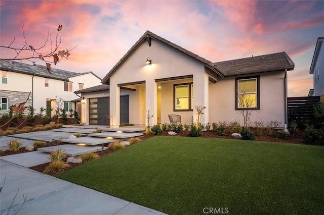 view of front of house featuring a garage, concrete driveway, a front lawn, and stucco siding