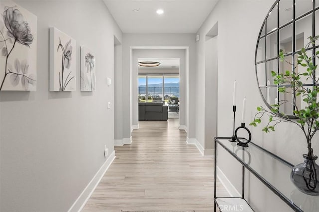 corridor featuring recessed lighting, light wood-style flooring, and baseboards