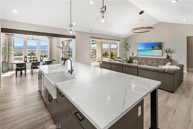 kitchen featuring open floor plan, modern cabinets, a sink, and light wood-style flooring