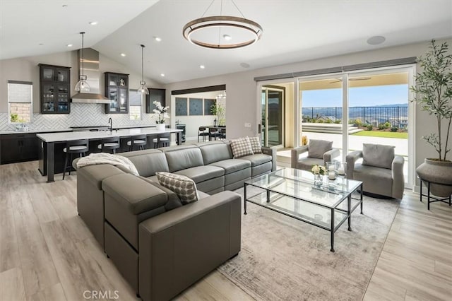 living area featuring light wood-style floors, vaulted ceiling, and recessed lighting