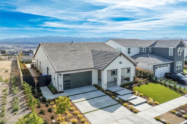 view of front of house featuring a garage, fence, a mountain view, and stucco siding