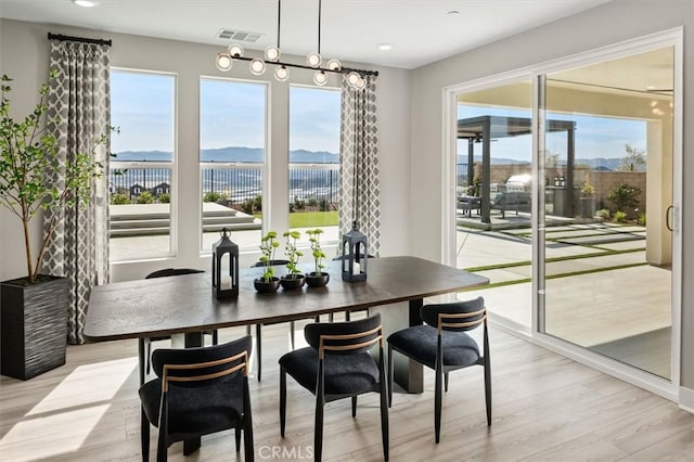 dining space with light wood-type flooring, visible vents, plenty of natural light, and a mountain view