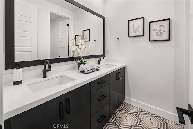 full bath with double vanity, a sink, and baseboards