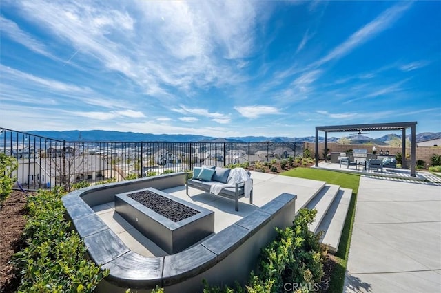 view of patio / terrace with fence, a mountain view, and an outdoor living space with a fire pit