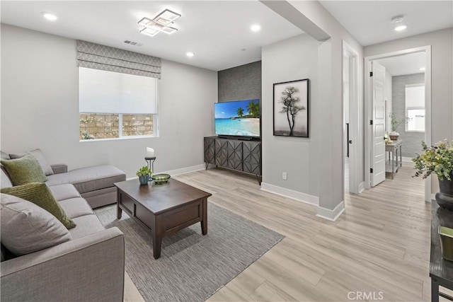 living area with light wood-style flooring, visible vents, baseboards, and recessed lighting