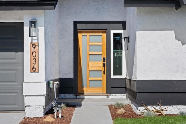 entrance to property with a garage and stucco siding