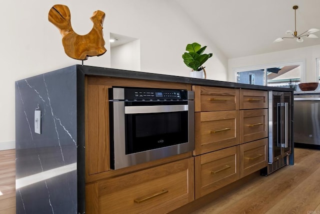 kitchen with lofted ceiling, light wood-style flooring, beverage cooler, stainless steel oven, and brown cabinetry