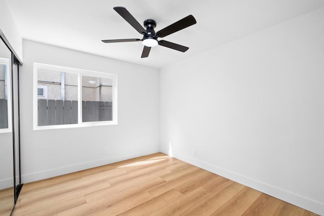 empty room featuring light wood-style floors, baseboards, and a ceiling fan