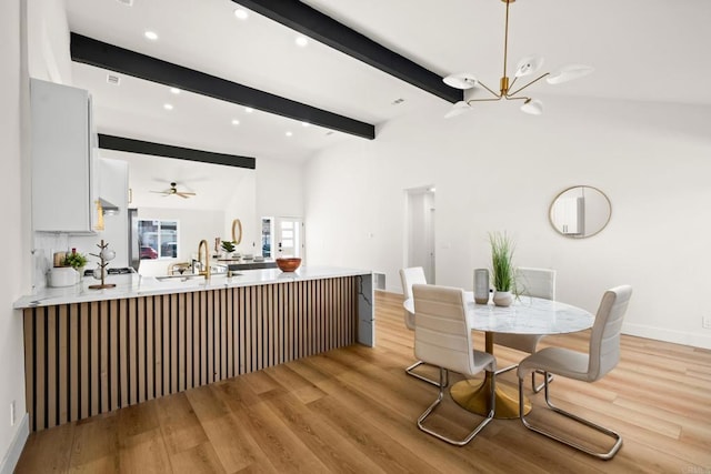 dining space featuring ceiling fan with notable chandelier, light wood-type flooring, beam ceiling, and recessed lighting