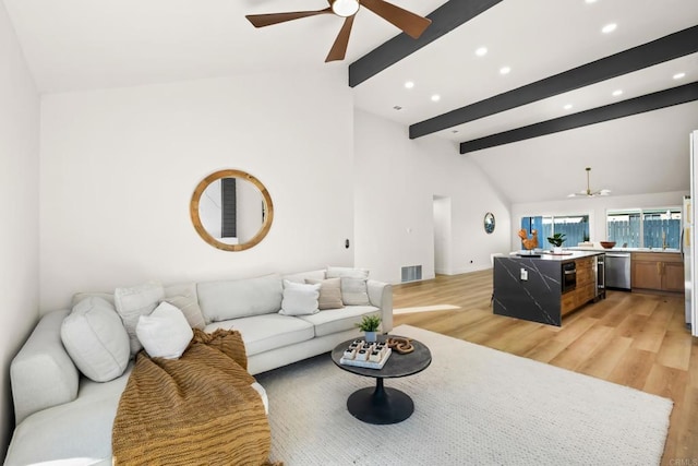 living room with light wood finished floors, ceiling fan, visible vents, and beam ceiling