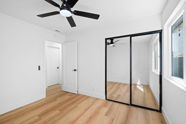 unfurnished bedroom featuring light wood finished floors, visible vents, baseboards, a ceiling fan, and a closet