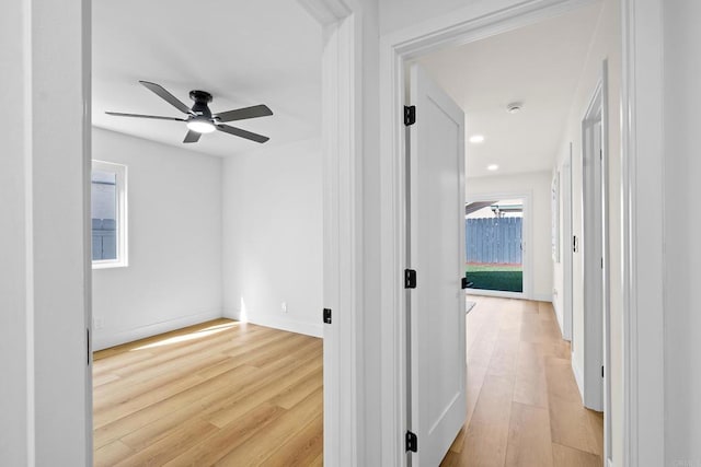 hallway with light wood-type flooring, baseboards, and recessed lighting