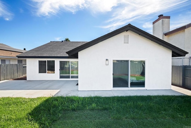 back of house featuring a yard, a patio area, fence, and stucco siding