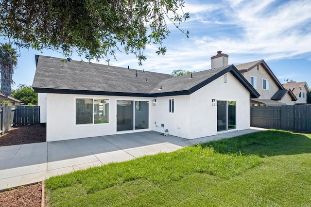 rear view of house with fence, a lawn, a patio, and stucco siding