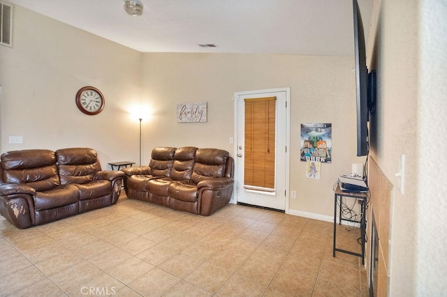 living area featuring lofted ceiling, light tile patterned floors, visible vents, and baseboards